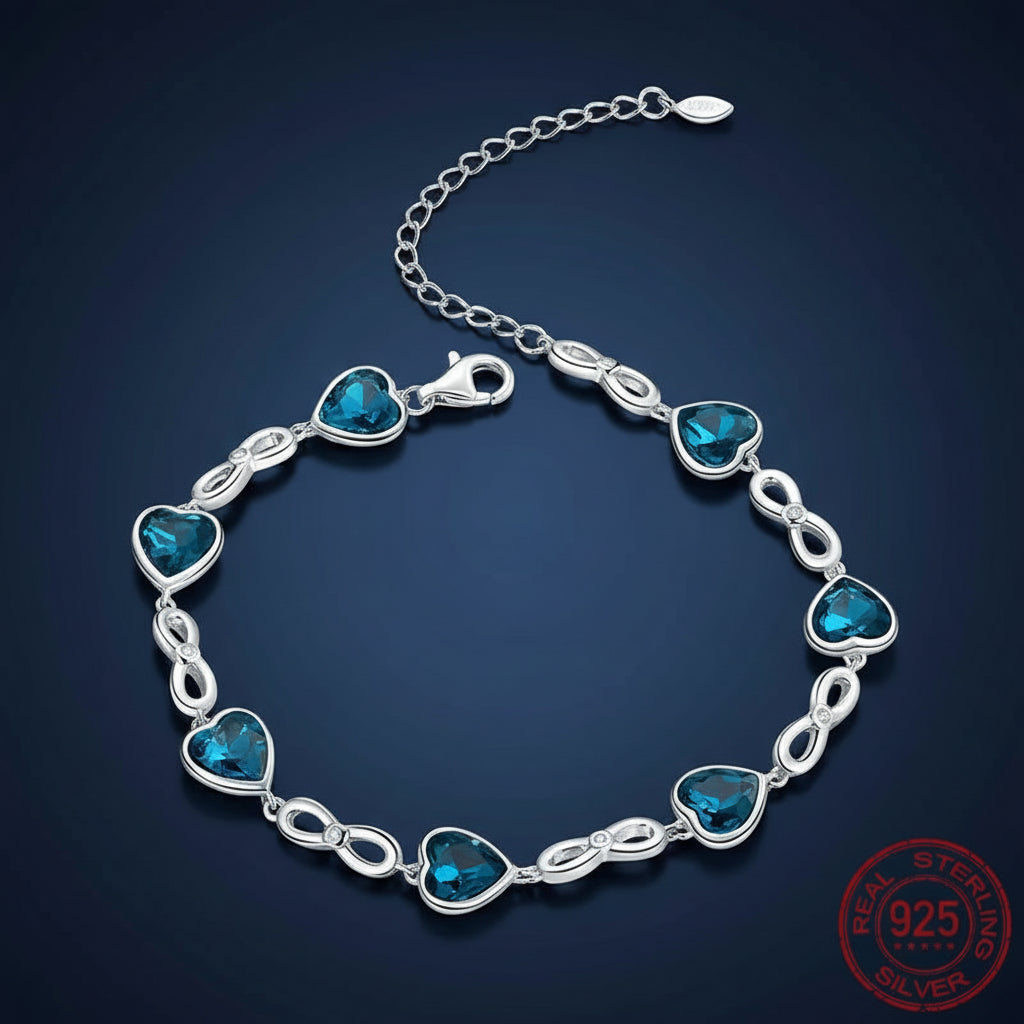 A sterling silver bracelet with heart-shaped blue gemstones and oval link details, displayed on a dark blue gradient background with a '925 Sterling Silver' stamp in the bottom right corner.