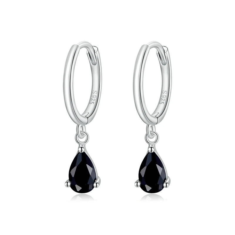 A pair of silver hoop earrings with green zircon stones attached to the hoops.