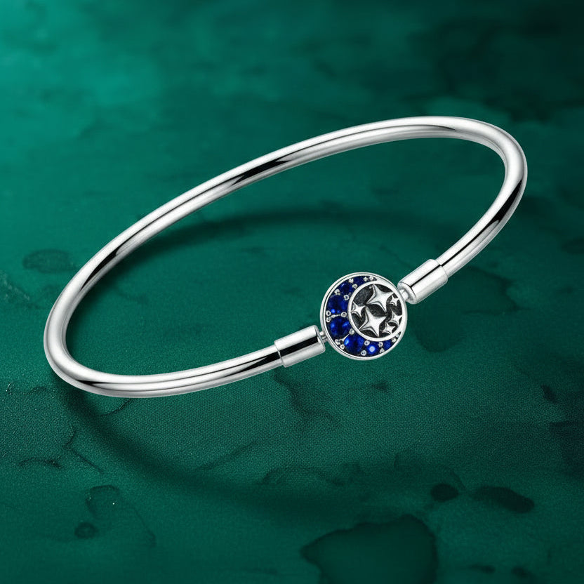 Silver bracelet with a circular star charm decorated with blue gemstones on a green textured background.