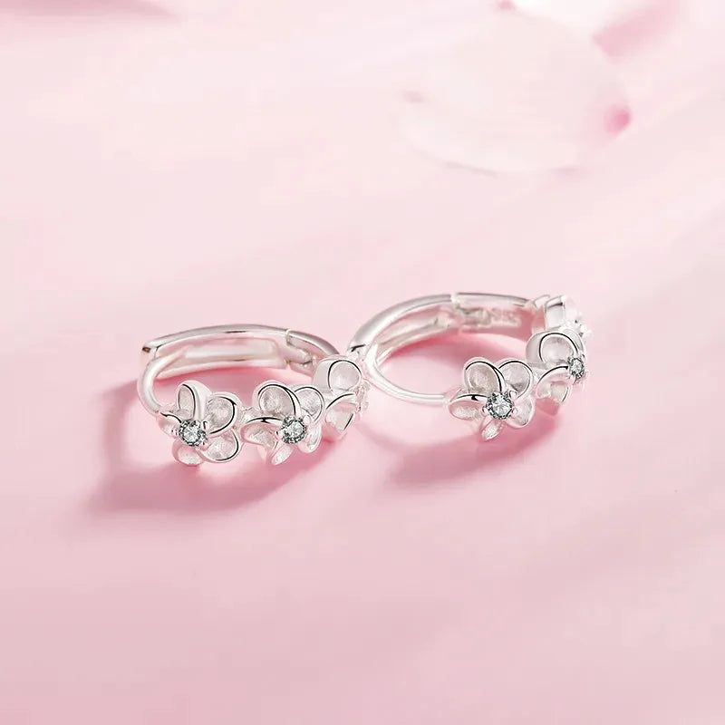 Silver floral hoop earrings on a pink background