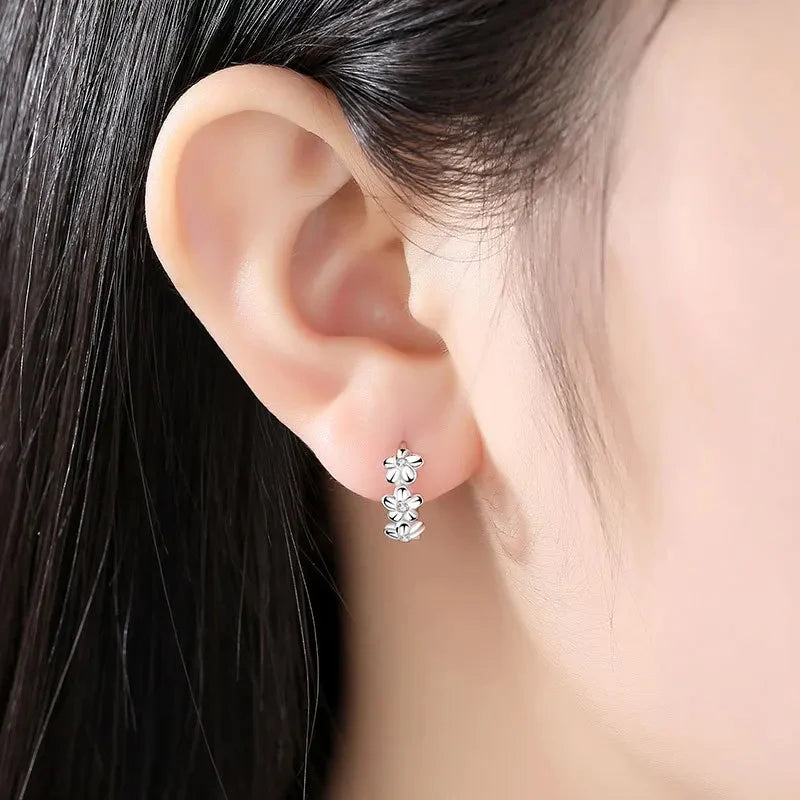 Close-up of an ear wearing a silver earring with clear stones.