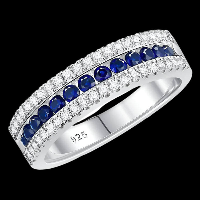 

925 sterling silver jewelry ring with a white gold finish, featuring a row of sapphire-blue crystals bordered by sparkling clear stones in an elegant eternity band design.


