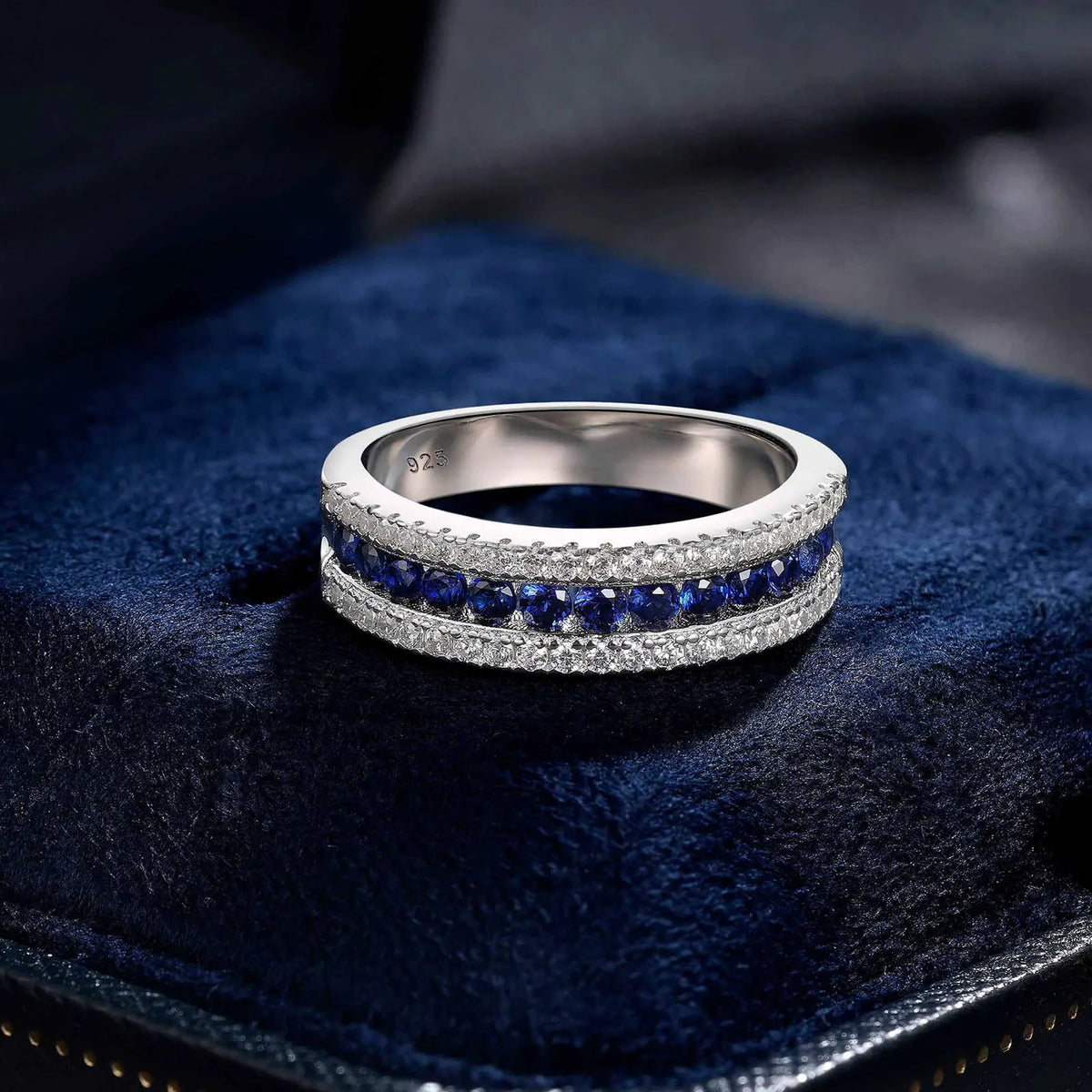 925 sterling silver jewelry ring with a white gold finish, featuring a row of sapphire-blue crystals bordered by sparkling clear stones in an elegant eternity band design.