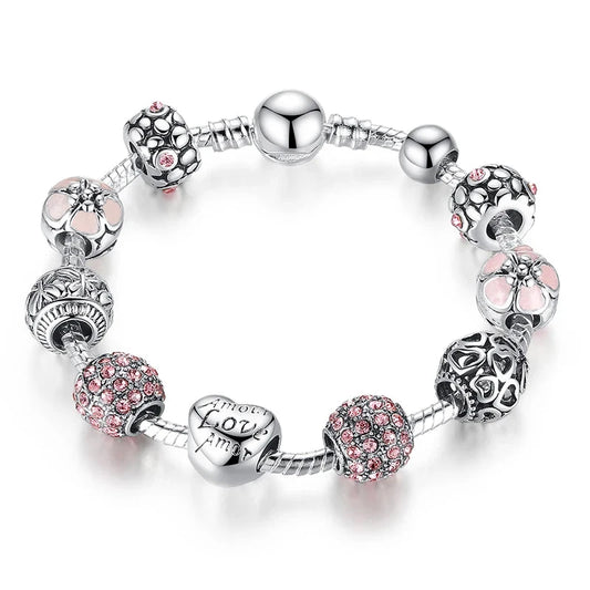 A silver-plated snake chain bracelet with various charms including heart-shaped and floral designs, adorned with crystals and metallic elements.