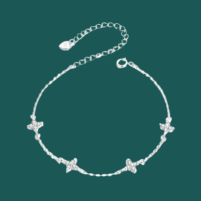 A sterling silver bracelet with white gold plating, featuring a chain design and adorned with small star-shaped charms.