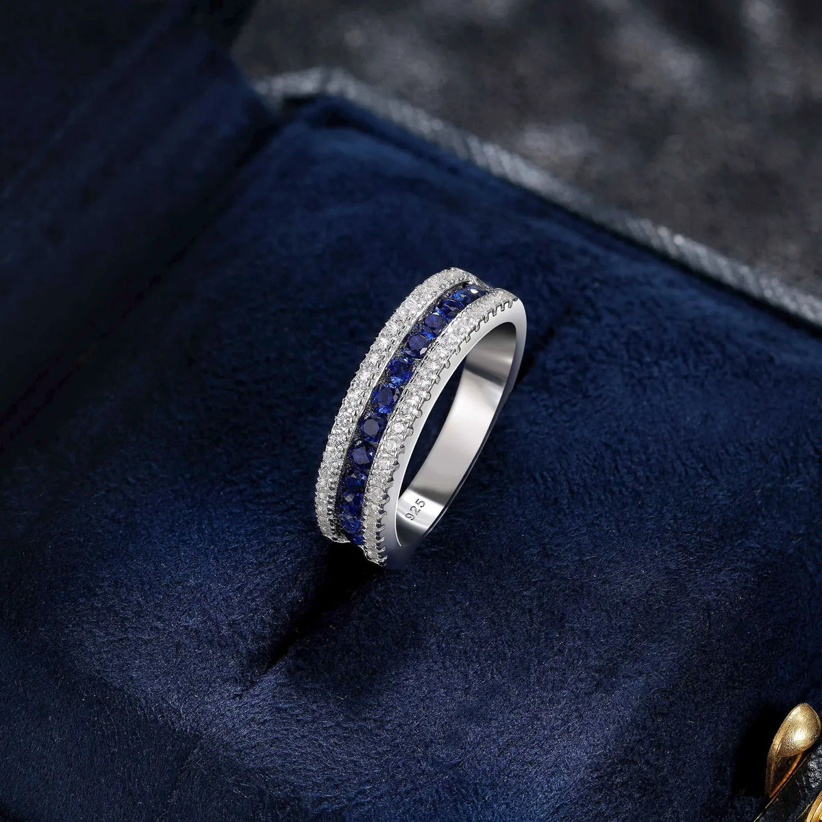 925 sterling silver jewelry ring with a white gold finish, featuring a row of sapphire-blue crystals bordered by sparkling clear stones in an elegant eternity band design.