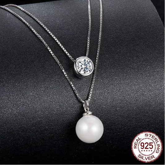 elegant piece of jewelry Double‑layer REAL 925 sterling silver necklace with a moissanite crystal pendant on the top chain and a white pearl drop on the lower chain, white gold‑plated finish, displayed on a dark textured background.