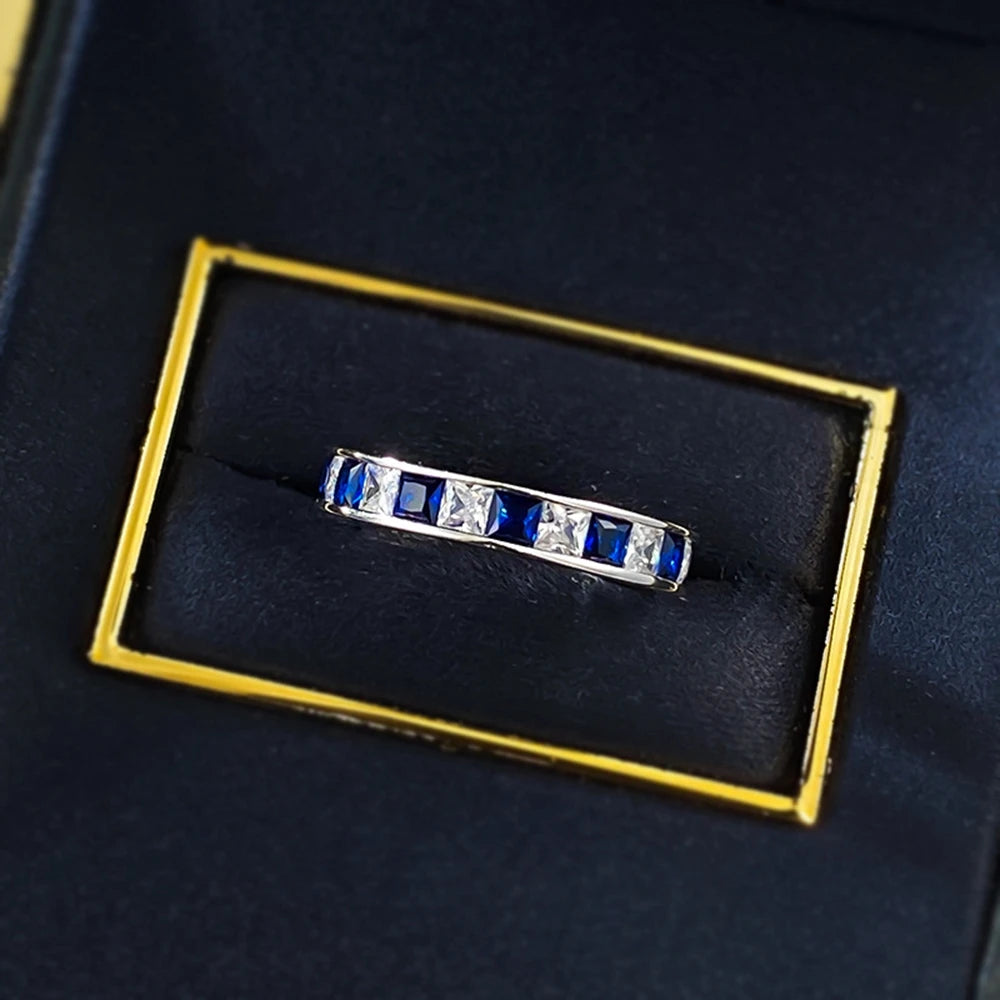 Jewelry 925 sterling silver eternity ring featuring sapphire main stones and 5A zircon high carbon diamond side stones in an elegant channel-set band design