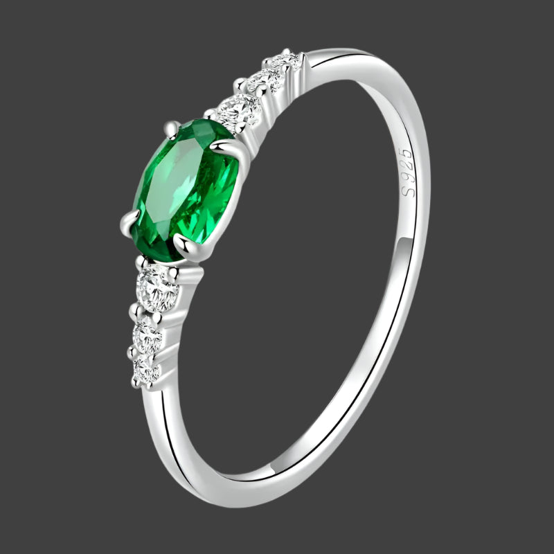 A 925 sterling silver ring with a single green gemstone in the center, flanked by two smaller white gemstones, set in a polished band.