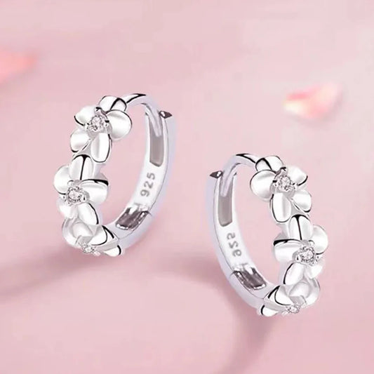 Silver hoop earrings with floral designs on a pink background